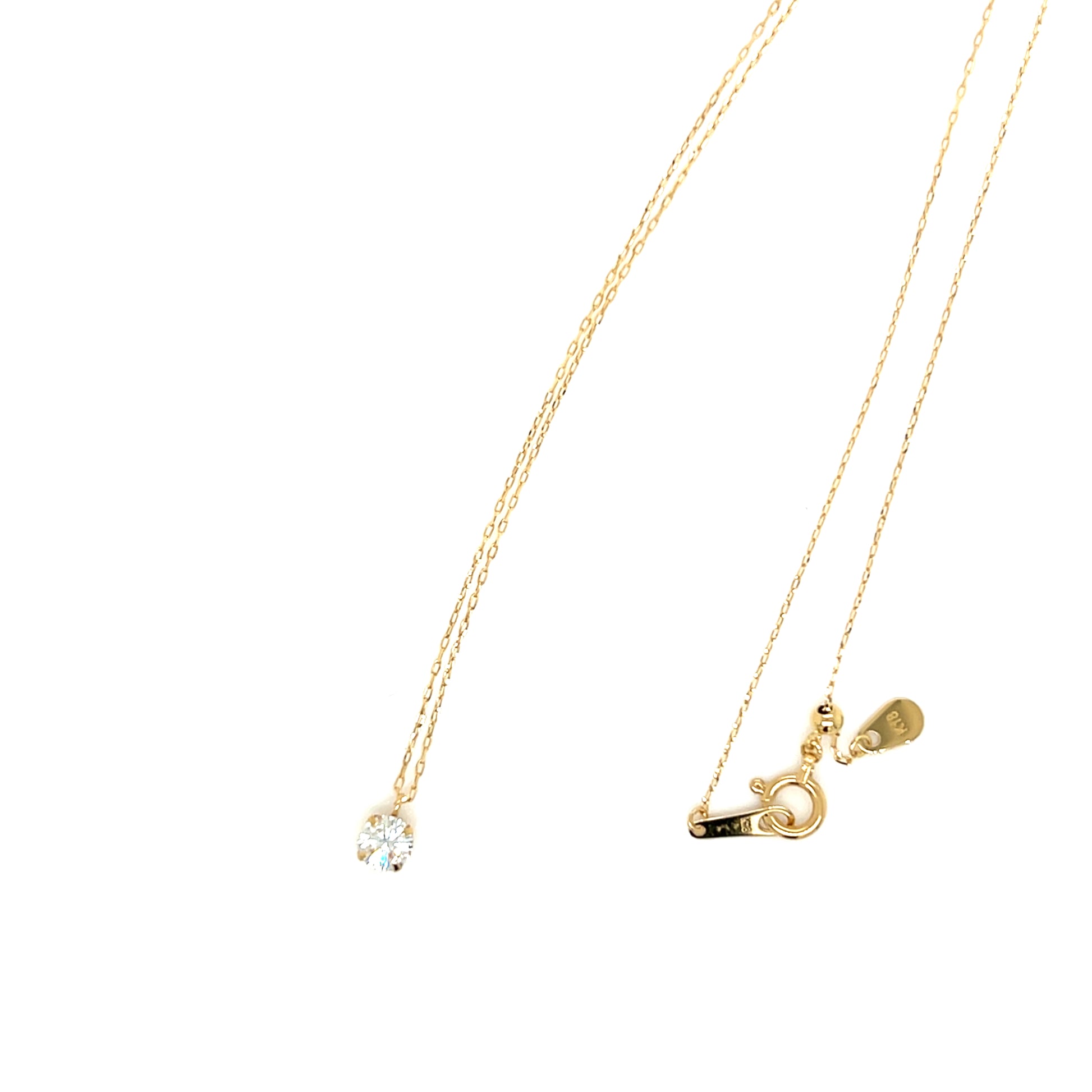 A delicate gold necklace with a small clear gemstone pendant on one side and a gold clasp with a small heart charm on the other, displayed against a solid white background.